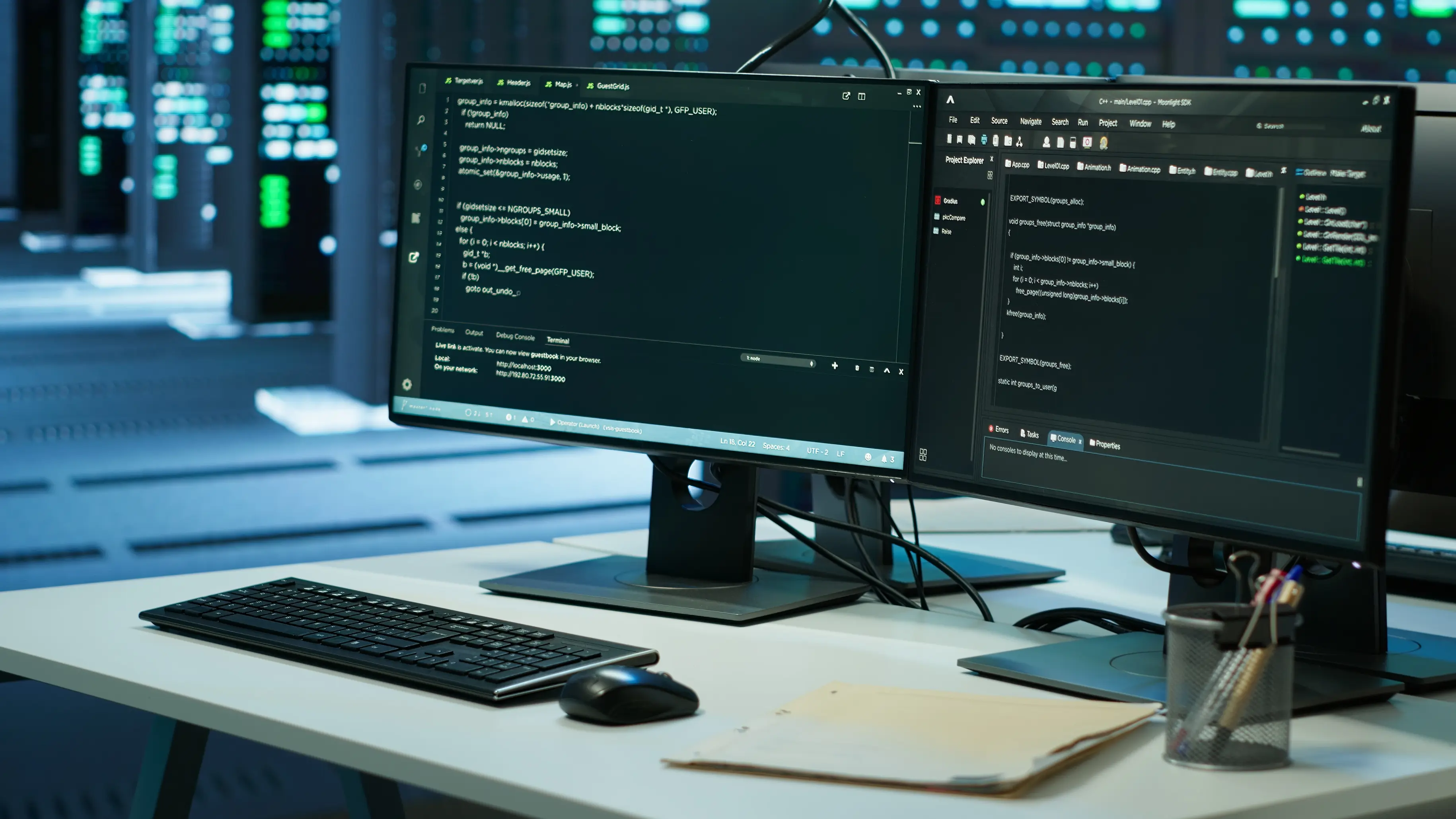 Dual monitors showing code, angled left view in a data center
