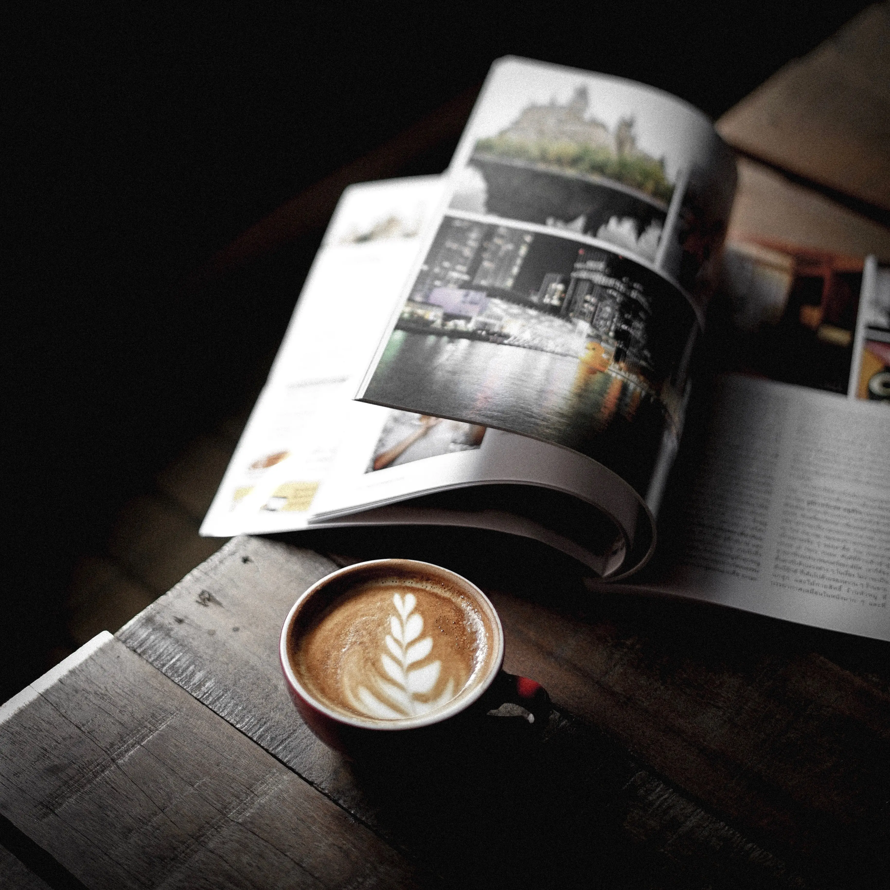 Kaffe bredvid en tidning på ett bord, sett snett ovanifrån