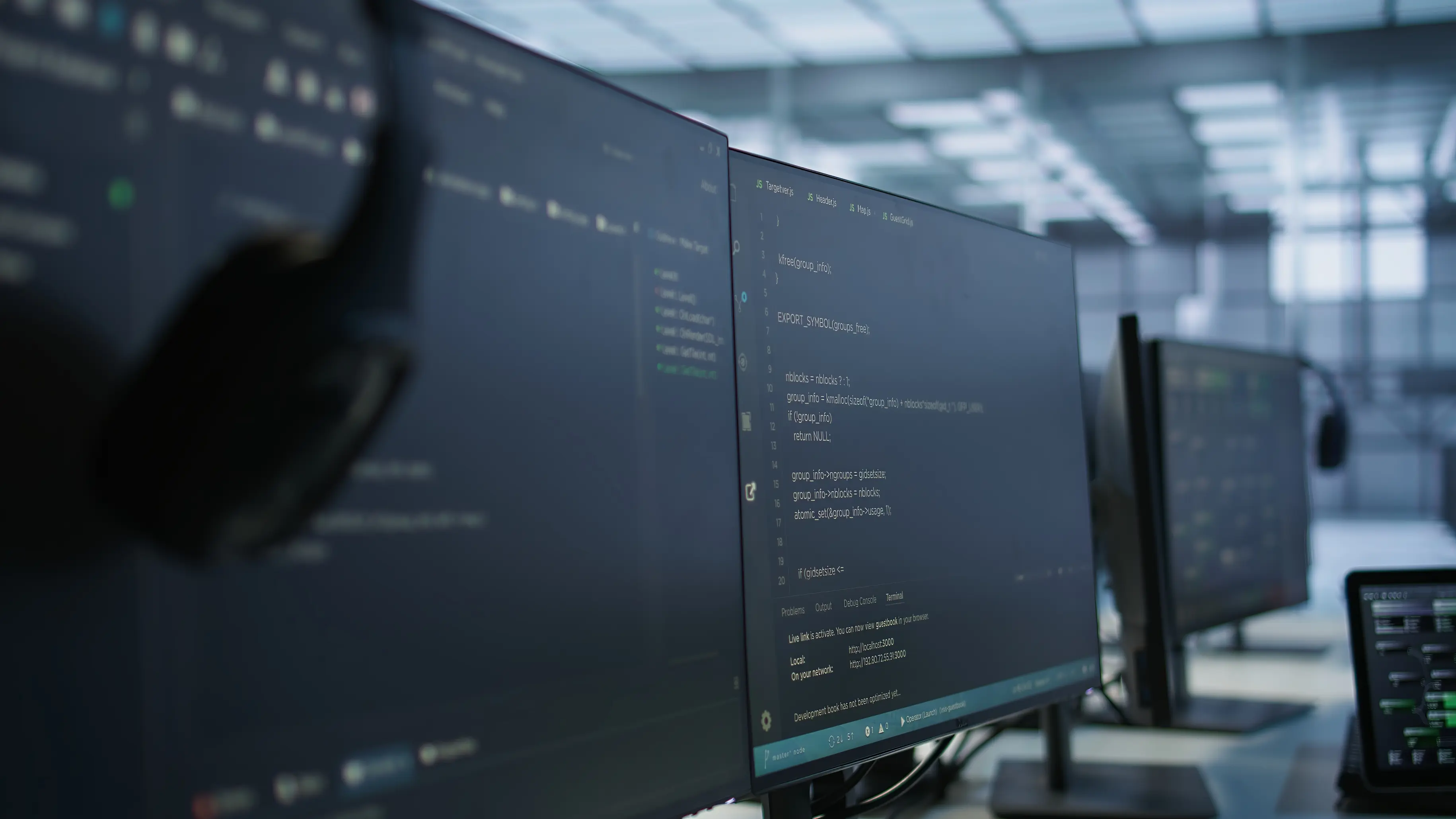 Monitors and headset showing code, close-up in a data center